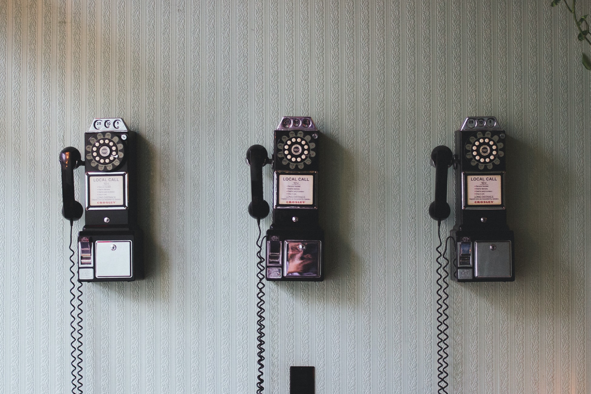 3 rotary phones on a wall